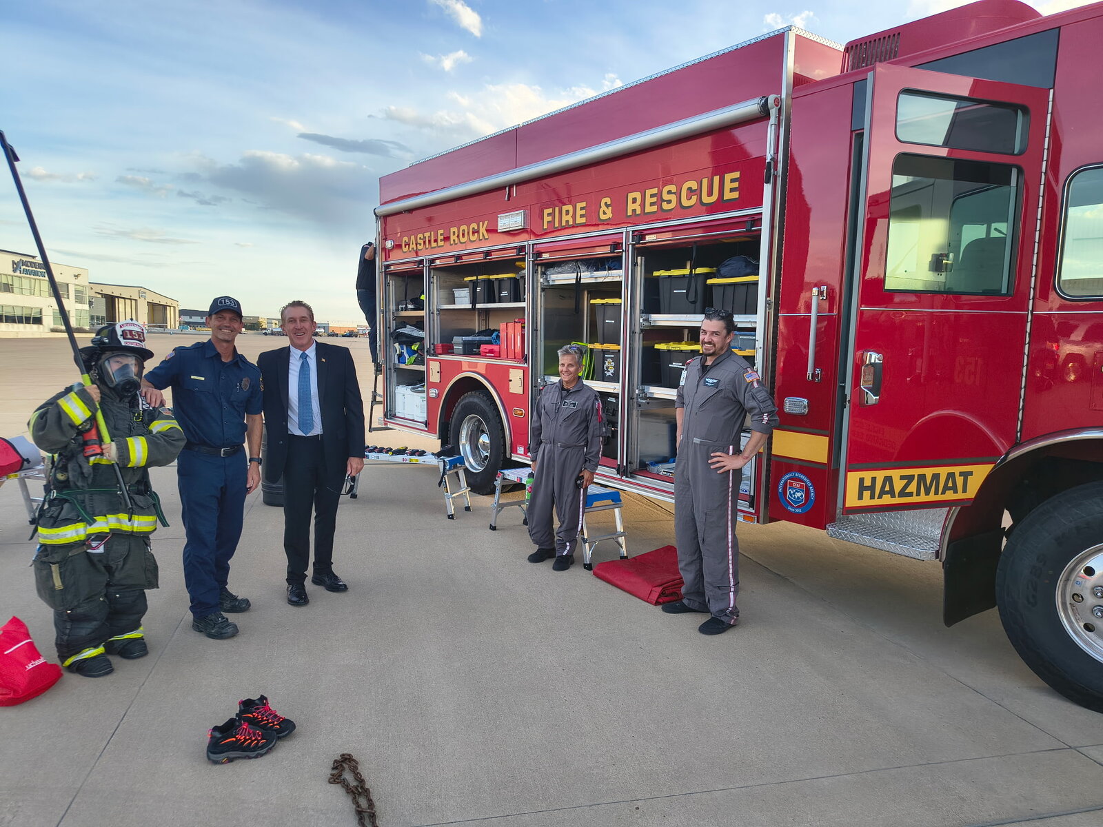 Tim Dietz with Castle Rock Fire & Rescue crew members beside their hazmat engine at the Heroes Gala, a young child trying on full firefighter turnout gear and a breathing mask